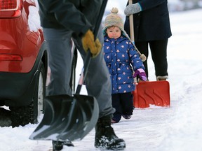 Two year-old Blake Gauthier supervises her parents Mike and Betty as they clear snow from their sidewalk along 6th avenue N.E. after an overnight snowfall on Sunday November 10, 2019.