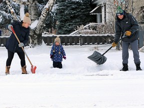 Two year-old Blake Gauthier supervises her parents Mike and Betty as they clear snow from their sidewalk along 6th avenue N.E. after an overnight snowfall on Sunday November 10, 2019.  Gavin Young/Postmedia