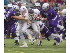 McMaster's Jordan Lyons runs behind the blocking of lineman Wyatt Croucher  before being stopped by the Mustangs defense during the Yates Cup at TD stadium on Saturday. Photo by Mike Hensen/Postmedia.