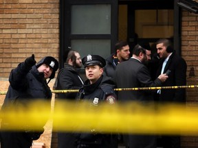 Police officers look at bullet holes in the windows of a school across the street from the JC Kosher Supermarket on December 11, 2019 in Jersey City, New Jersey.