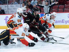 Flames players surround Arizona Coyotes centre Clayton Keller during a game on Nov. 16, 2019.