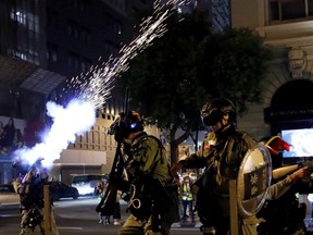 A riot police officer shoots tear gas to disperse anti-government demonstrators protesting on Christmas Eve in Hong Kong, China, Tuesday, Dec. 24, 2019.