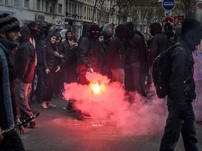 A man dressed in black and burning a flare takes part in a demonstration in Lyon on Dec. 17, 2019 to protest against French government's plan to overhaul the country's retirement system, as part of a national general strike.