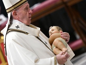 Pope Francis carries a statue of baby Jesus during a mass on Christmas Eve, marking the birth of Jesus Christ on Dec. 24, 2019, in St Peter's basilica at the Vatican.