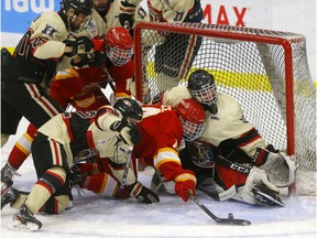 The Calgary Flames' Hunter Price battles with Red Deer Optimist Chiefs goalie Logan Breen during Mac's AAA Midget Hockey Tournament action at Father Bauer Arena in Calgary on Monday. Photo by Darren Makowichuk/Postmedia.