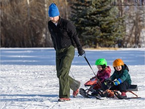 Siblings four-year-old Maximo, and two-and-a-half-year-old Vittoria, enjoy a ride on their sleds as their father Nathan Salmon pulls them to the top of the hill on a beautiful sunny day in Confederation park on Tuesday, January 21, 2020. Azin Ghaffari/Postmedia