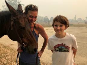 Bec Winter stands next to her son, Riley, while hugging her horse Charmer, who she rode to safety through bushfires on New Year's Eve, in Moruya, Australia Jan. 4, 2020. (REUTERS/Jill Gralow)