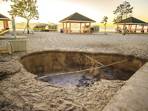 A sinkhole is surrounded by police tape after it appeared when a powerful magnitude 7.7 earthquake struck in the Caribbean Sea between Jamaica and eastern Cuba, at Public Beach on Grand Cayman, Tuesday, Jan. 28, 2020. (Taneos Ramsay/Cayman Compass via AP)