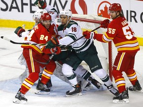 Travis Hamonic battles two Minnesota Wild players in the Flames crease on Jan. 9, 2020.