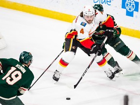 Flames defenceman Rasmus Andersson protects the puck against the Minnesota Wild.