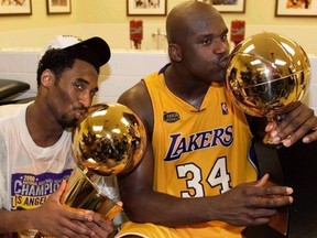 Los Angeles Lakers center Shaquille O'Neal kisses the Most Valuable Player trophy as teammate Kobe Bryant kisses the NBA championship trophy as they celebrate in the locker room after winning the NBA Finals against the Indiana Pacers, June 19, 2000.