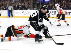 Dustin Brown #23 of the Los Angeles Kings skates with the puck past  the defense of Noah Hanifin #55 of the Calgary Flames during the second period of a game at Staples Center on February 12, 2020 in Los Angeles, California.