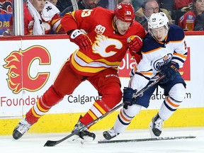 Edmonton Oilers Kailer Yamamoto and the Calgary Flames Buddy Robinson fight for position during NHL action in Calgary on Saturday, February 1, 2020.