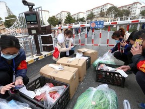 Volunteers and community workers deliver vegetables and goods to residents inside a residential compound at its entrance, in Xiangyang city of Hubei, the province hit hardest by the novel coronavirus outbreak, China February 20, 2020.