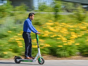 A Lime e-scooter rider commutes on Riverwalk in East Village on Monday, July 29, 2019. Azin Ghaffari/Postmedia Calgary