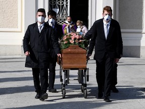Pallbearers wearing protective masks carry the coffin of a woman who died from coronavirus disease (COVID-19) at her funeral, as Italy struggles to contain the spread of coronavirus disease (COVID-19), in Seriate, Italy March 28, 2020. (REUTERS/Flavio Lo Scalzo)