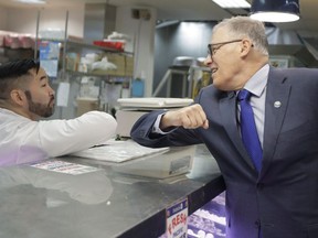 Washington Gov. Jay Inslee, right, bumps elbows with a worker at the seafood counter of the Uwajimaya Asian Food and Gift Market, Tuesday, March 3, 2020, in Seattle's International District.