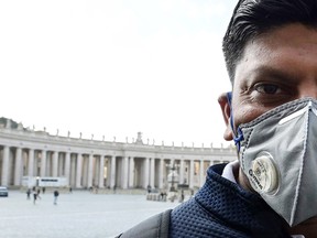 A man wearing a protective mask walks past a deserted St. Peter's square at the Vatican on March 6, 2020.
