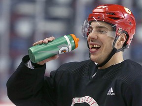 Flames Travis Hamonic shares a laugh as he takes a sip of water at the bench during Calgary Flames practice in Calgary on  Tuesday, March 10, 2020.