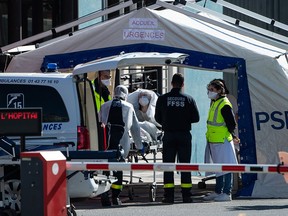 Doctors tend to a patient arriving on a wheelchair at the reception of the Emergency Room, set up in a tent, in a courtyard of the Henri Mondor Hospital in Creteil, near Paris, on March 30, 2020,.