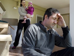 Young parents and their daughter stand beside cardboard boxes outside their home. Concept photo illustrating divorce, homelessness, eviction, unemployment, financial, marriage or family issues.