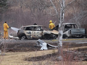 A Wentworth volunteer firefighter douses hotspots near destroyed vehicles linked to Sunday's deadly shooting rampage on April 20, 2020 in Wentworth Centre, N.S.