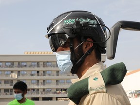 A police officer wears a smart helmet as he uses it to check the temperature of workers during the outbreak of the coronavirus disease (COVID-19) in Dubai, United Arab Emirates April 23, 2020.