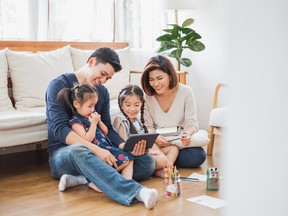 Happy Asian family using tablet, laptop for playing game watching movies, relaxing at home for lifestyle concept