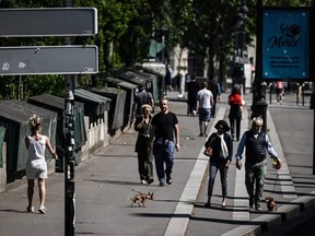 People walk along the banks of the Seine River during a sunny day in Paris on Sunday, April 26, 2020 despite a strict lockdown to stop the spread of COVID-19.