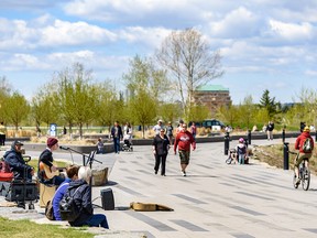 Riley Feist busks on a crowded Bow River pathway as people enjoy the pleasant weather on Wednesday, May 13, 2020.