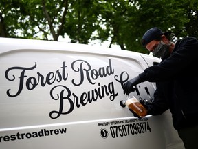 Director of Forest Road Brewing Co Peter Brown pours a customer a pint of beer from the Forest Road Brewing Co pub on wheels vehicle during his delivery round in Hackney, as the coronavirus disease (COVID-19) spread continues in London, May 12, 2020.