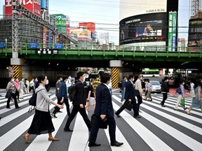 People wearing face masks cross a street in Tokyo on May 25, 2020. - Japan's prime minister was expected later on May 25 to lift the state of emergency in the Tokyo region, after last week lifting it for the region around Osaka and Kyoto.