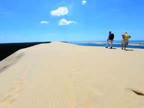 People walk on Europe's tallest sand dune called "Dune du Pilat" in La Teste-de-Buch, near the Arcachon Bay on May 28, 2020 as France eases lockdown measures taken to curb the spread of the COVID-19 (the novel coronavirus).