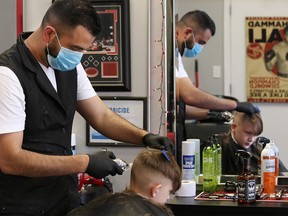FILE PHOTO: Moe Charanek cuts 12-year-old Cory Flaig’s hair at the Six Barbers barbershop in Calgary on Monday, May 25, 2020.