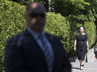 A security guard looks on as Meng Wanzhou, chief financial officer of Huawei, leaves her home to go to B.C. Supreme Court in Vancouver, Wednesday, May 27, 2020.
