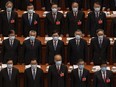 Chinese Communist Party delegates, all wearing protective masks, stand during the national anthem at the opening of the National People's Congress at the Great Hall of the People on May 22, 2020, in Beijing.