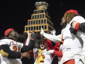 University of Calgary Dinos' Adam Sinagra, centre, raises the trophy with teammates Jeshrun Antwi, left, and Sterling Taylor IV after winning the U Sports Vanier Cup university football championship against the University of Montreal Carabins, in Quebec City, Sunday, Nov. 23, 2019. THE CANADIAN PRESS/Jacques Boissinot