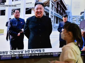 A woman walks past a television news screen showing a picture of North Korean leader Kim Jong Un attending a ceremony to mark the completion of Sunchon phosphatic fertiliser factory, at a railway station in Seoul on May 2, 2020.
