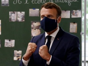 French President Emmanuel Macron, wearing a protective mask, gestures as he speaks to pupils during a visit at the Pierre Ronsard elementary school in Poissy, on May 5, 2020.