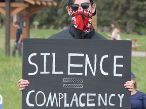 A supporter is seen holding a sign during a Rise Up Against Racism protest in Fish Creek Park. Protestors gathered in solidarity to support of George Floyd, who died while a Minneapolis police officer kneeled on his neck. Sunday, May 31, 2020.