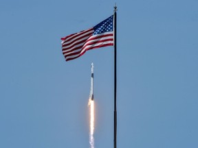 An American flag is seen as SpaceX Falcon 9 rocket and Crew Dragon spacecraft carrying NASA astronauts Douglas Hurley and Robert Behnken lifts off during NASA's SpaceX Demo-2 mission to the International Space Station from NASA's Kennedy Space Center in Cape Canaveral, Florida, U.S. May 30, 2020. REUTERS/Thom Baur ORG XMIT: KSC