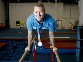 Kyle Shewfelt wears his Olympic gold medal while monkeying around on the parallel bars inside his gymnastics facility in southeast Calgary, Alta., on Thursday, Aug. 21, 2014.