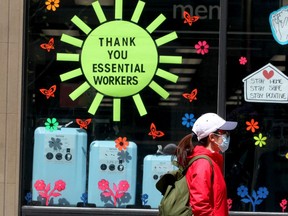 A woman walks past a sign thanking essential workers along Stephen Avenue during the COVID-19 pandemic in Calgary on Wednesday, May 27, 2020.