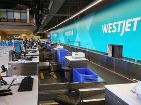 A WestJet employee checks in a passenger with a row of empty stations at the Calgary International Airport on Wednesday, June 24, 2020. WestJet announced the layoff of 3333 employees Wednesday in the continuing fallout from the COVID-19 pandemic.