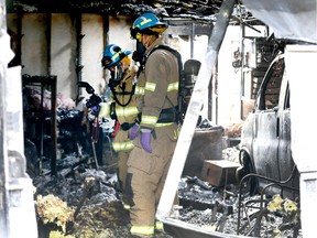 Calgary Fire Department investigators sift through the aftermath of a garage fire in 300 block of Whitney Cr SE in Calgary on Saturday, June 27, 2020. Neighbors reported hearing explosions and the sound of bullets going off in the garage. On scene crews were able to confirm that there were batteries, ammunition and propane cylinders in the detached garage.