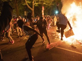 Protesters jump on a street sign near a burning barricade during a demonstration against the death of George Floyd near the White House on May 31, 2020 in Washington, DC.