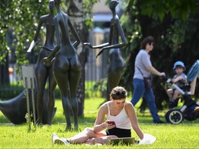 A young woman rests on a lawn at the Muzeon Park of Arts in Moscow on June 9, 2020, on the first day after Moscow lifted a range of anti-coronavirus measures including a strict lockdown set up to curb the spread of the COVID-19 caused by the novel coronavirus.