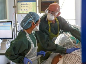 Medical staff wearing full personal protective equipment treat a patient with COVID-19, in an Intensive Care Unit ward at Frimley Park Hospital in Frimley, England, May 22, 2020.