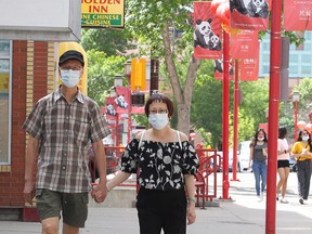 A couple is seen walking along 2nd Ave. SE while wearing masks in Chinatown. Monday, June 22, 2020.