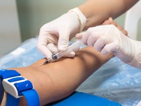 nurse with syringe is taking blood for test at the
